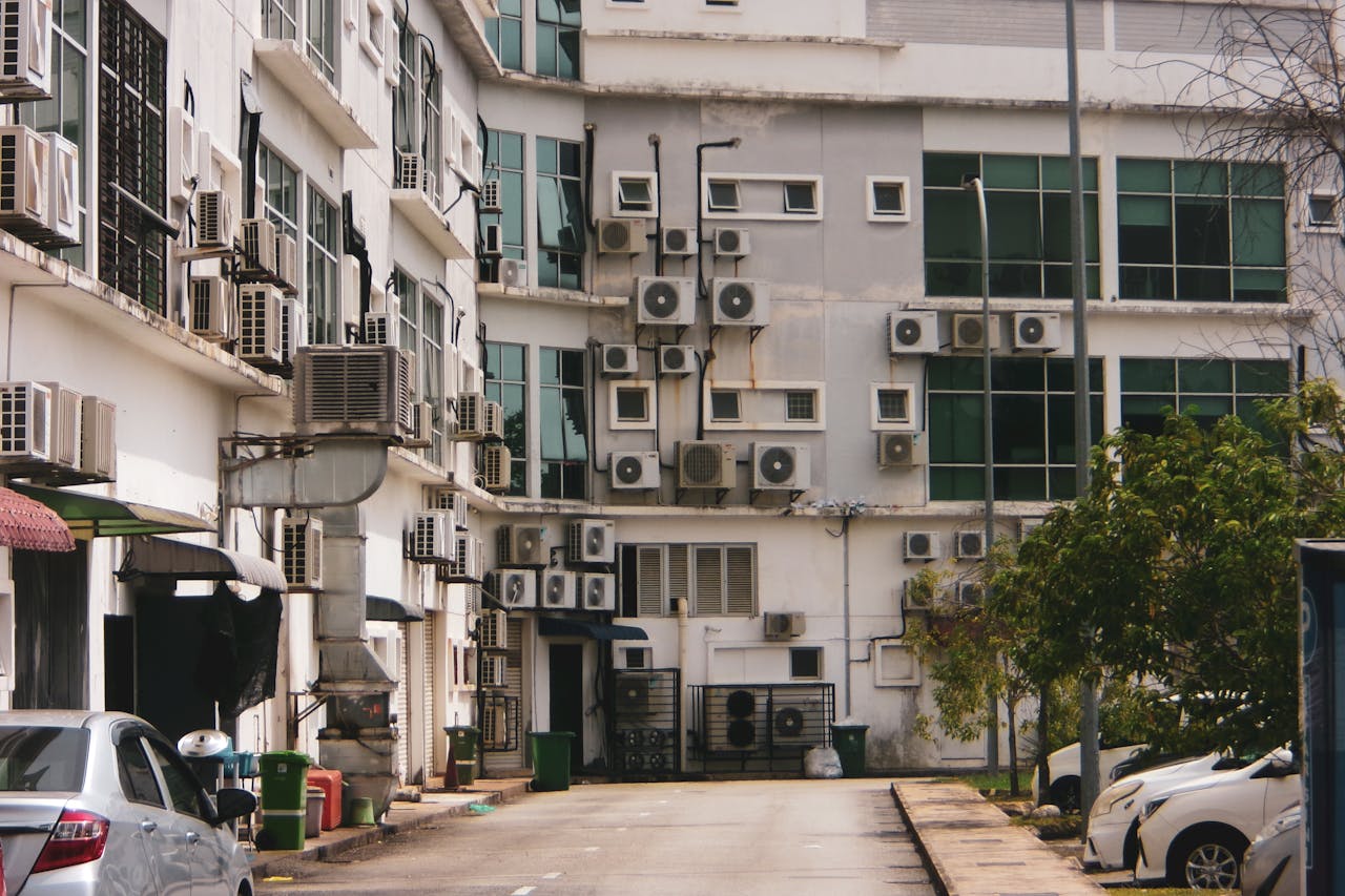 Exterior view of a building with multiple air conditioners and parked cars