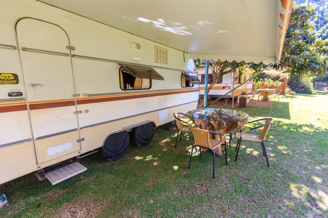 Vintage caravan with outdoor seating area under awning on a sunny day.